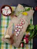 Free photo top view of white and red radishes on cutting board with knife on cloth surface and maroon background