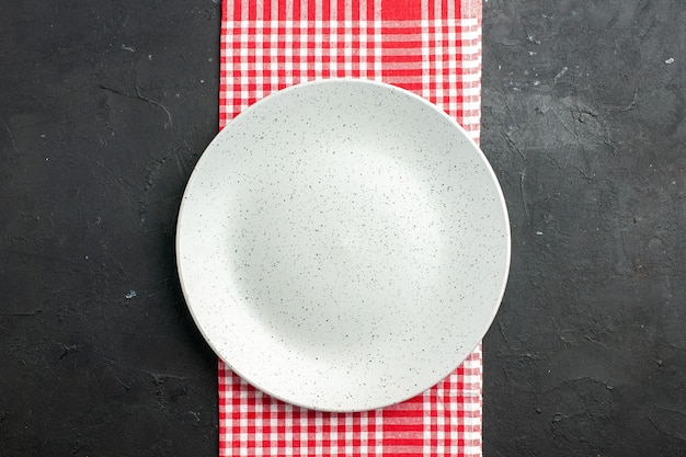 Free photo top view white round plate on red and white checkered napkin on dark table copy place