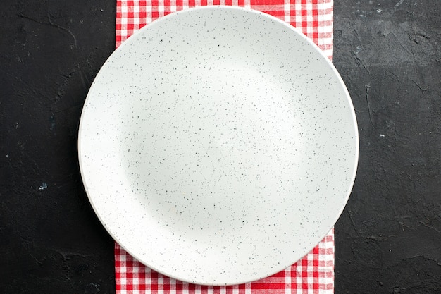 Free photo top view white round plate on red and white checkered napkin on dark table