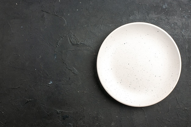 Top view white salad plate on dark table with free space