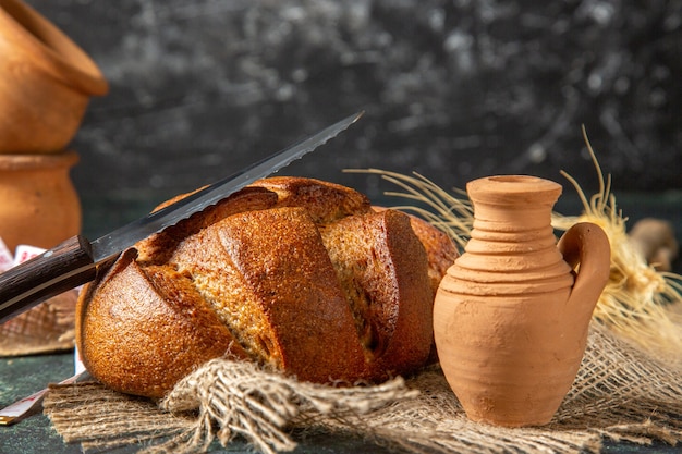 Top view of whole black bread on brown towel potteries on dark wall