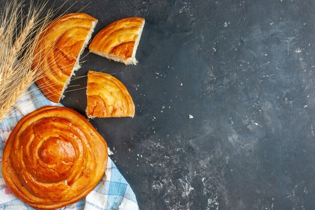 Top view of whole and cut delicious pastries on blue stripped towel and spike on the left side on blue