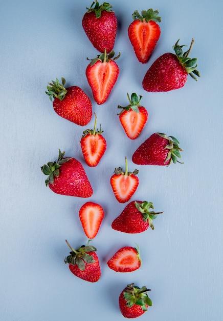 Free photo top view of whole and cut strawberries on blue surface