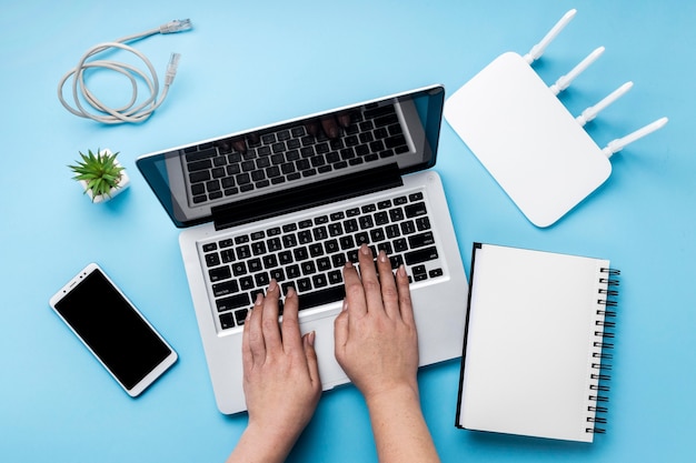 Top view of wi-fi router with hands using laptop and smartphone