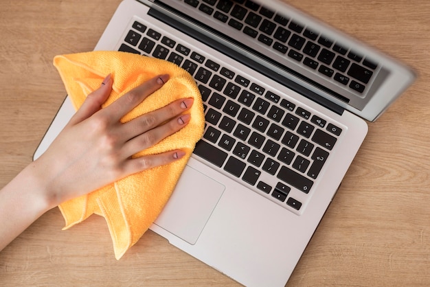 Free photo top view of woman cleaning laptop with cloth