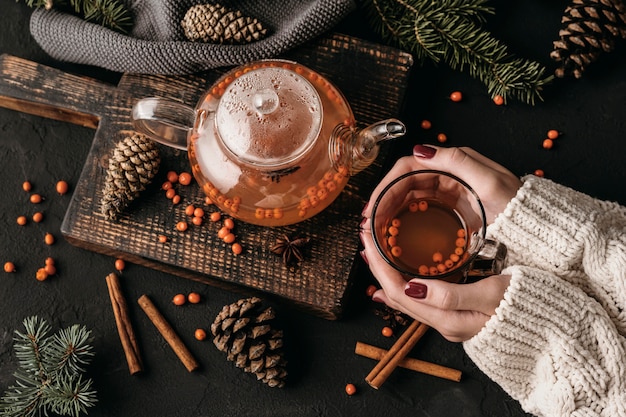 Top view woman holding glsss with sea buckthorn tea