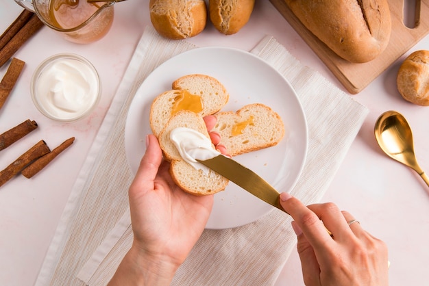 Top view woman spreading cream cheese on bread