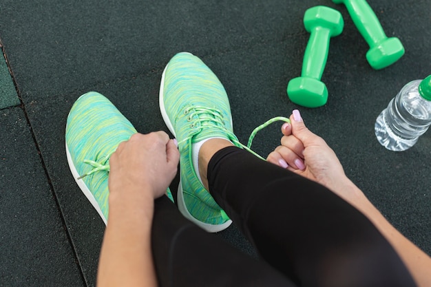 Free photo top view woman tying her green sneakers