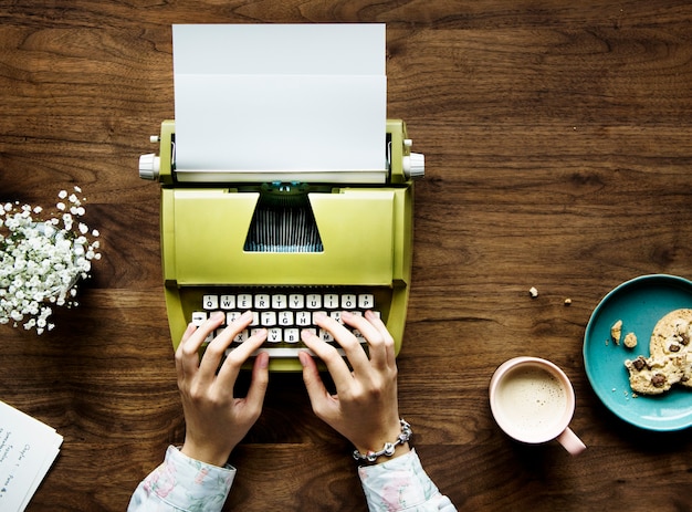 Free photo top view of a woman typing on a retro typewriter blank paper