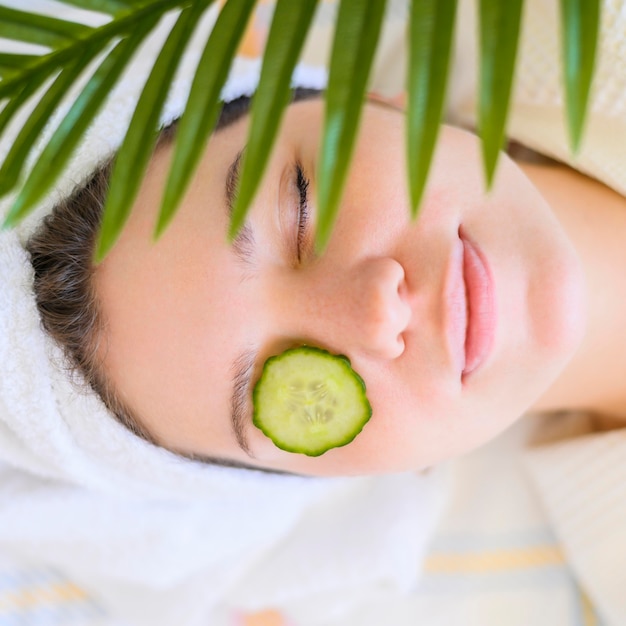 Top view of woman with cucumber slice on eye