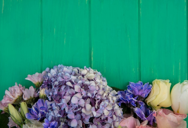 Top view of wonderful colorful flowers like gardenzia daisy rose on a green wooden background with copy space