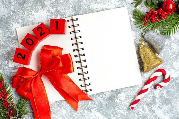 Top view wood blocks red bow on notepad xmas bells xmas candy on grey white background