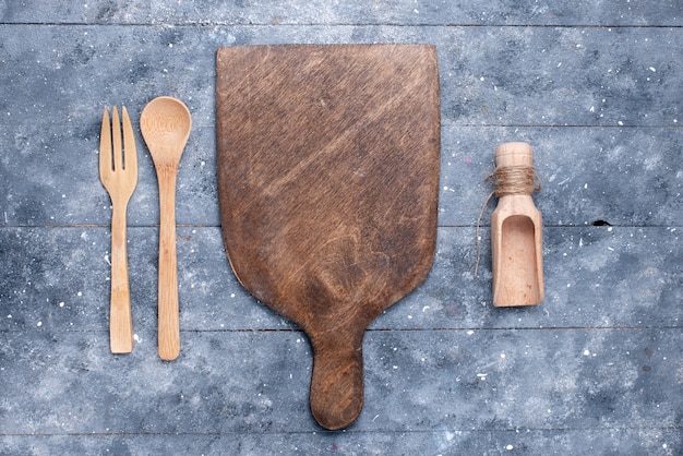 Free photo top view wooden cutlery with brown wooden desk on the blue background spoon fork color photo kitchen