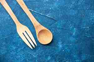 Free photo top view wooden fork spoon on blue table free place