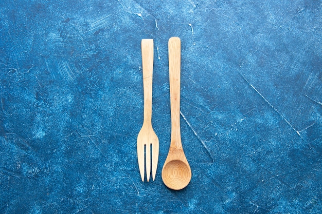 Free photo top view wooden fork spoon on blue table with free space