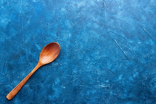 Top view wooden spoon on blue ground with copy space