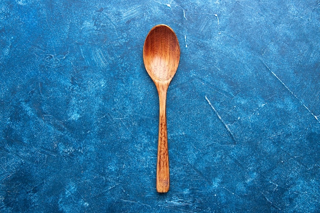 Free photo top view wooden spoon on blue table copy place