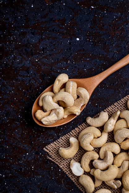 Top view of a wooden spoon with cashew on black background