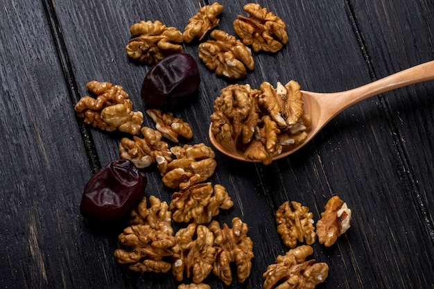 Top view of a wooden spoon with walnuts and sweet dried date fruits on rustic