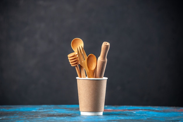 Top view of wooden spoons in an empty plastic coffee pot on blue surface