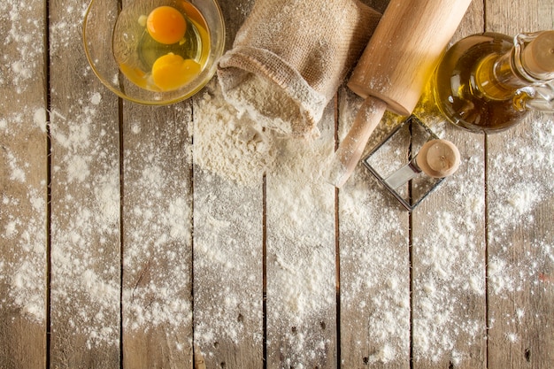 Top view of wooden surface with flour, eggs and rolling pin