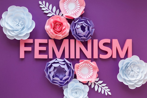 Free photo top view of the word feminism with paper flowers for women's day