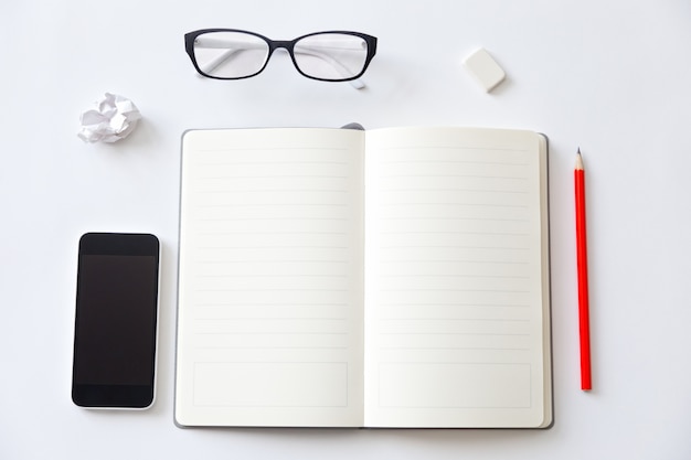 Top view of a working desk with open blank notebook