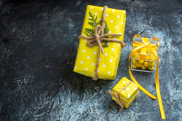 Free photo top view of xmas background with beautiful yellow gift boxes on the left side on dark table