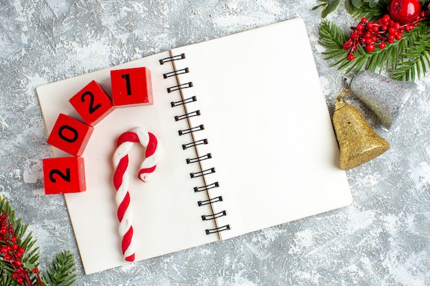 Free Photo top view xmas candy wood blocks on notepad xmas bells xmas red belly on grey white table