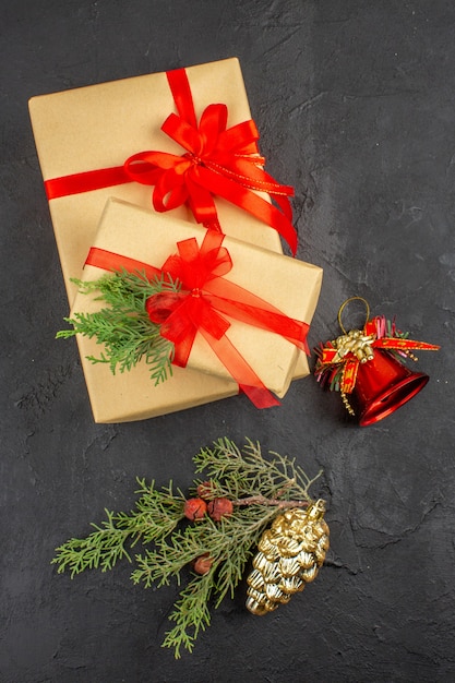 Top view xmas gift in brown paper tied with red ribbon branch fir xmas tree ornaments on dark background