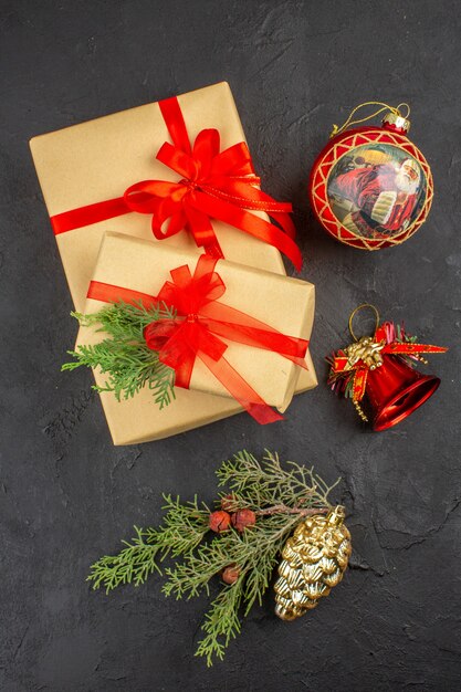 Top view xmas gift in brown paper tied with red ribbon xmas tree ornaments on dark background