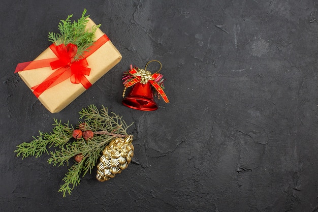 Top view xmas gift in brown paper tied with red ribbon xmas tree pendants on dark background copy space