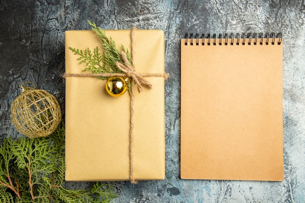 Top view xmas gift pine branches xmas ball notebook on grey surface