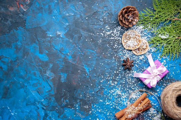 Top view xmas gifts fir tree branches cones anises on blue surface