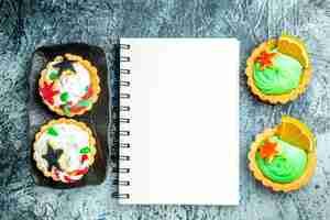 Free photo top view xmas tarts on black plate xmas candy notebook on grey table