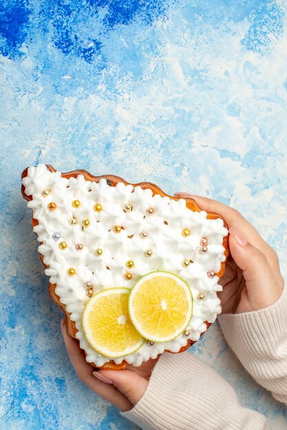 Top view xmas tree cake in female hand on blue table free space