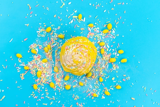 Free photo a top view yellow cake with candies on blue