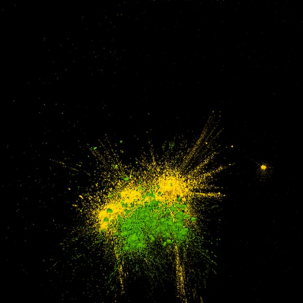 Top view of yellow and green holi colored powder over black backdrop