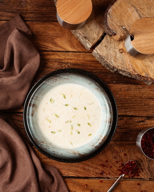 A top view yogurt soup inside black plate on the wooden desk food meal soup