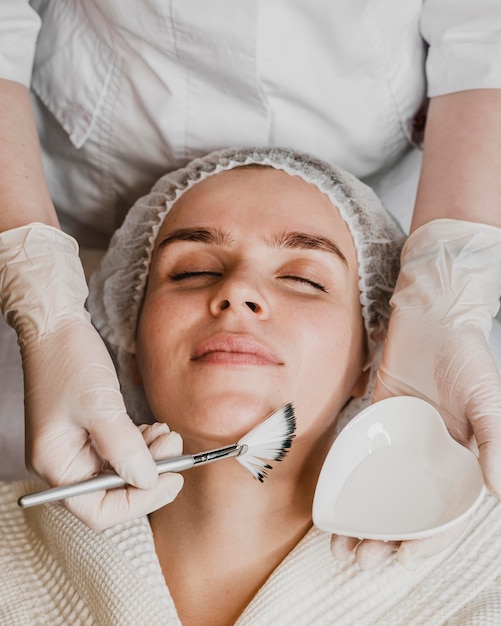 Top view of young beautiful woman getting a face skin treatment