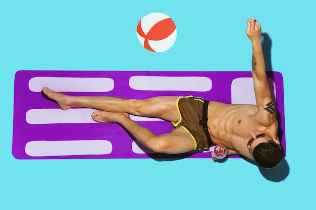 Top view of young caucasian male model's resting on beach resort on purple mat