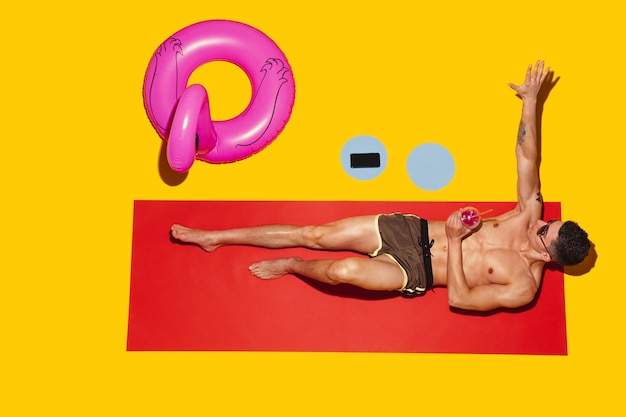 Top view of young caucasian male model's resting on beach resort on red mat and yellow