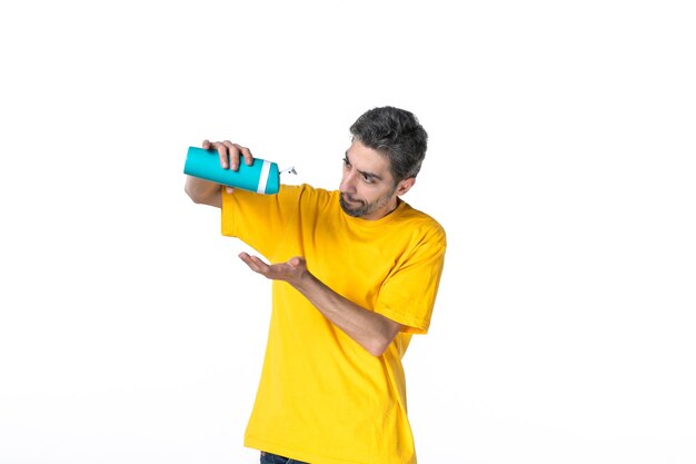 Top view of young male in yellow shirt holding thermos and checking it on white background