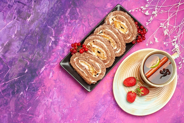 Top view yummy biscuit rolls with cup of tea on pink background