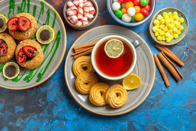 Top view yummy biscuits with cup of tea and candies on the blue cookie sweet fruit