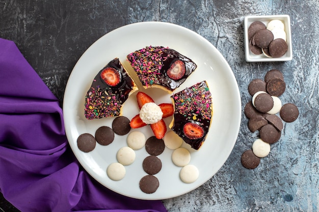 Top view yummy cake slices with choco cookies on dark surface