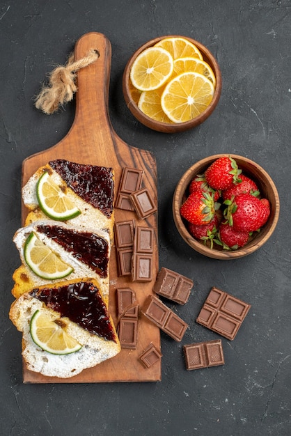 Free Photo top view yummy cake slices with chocolate and fruits on a dark surface