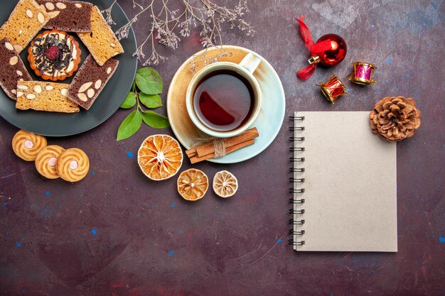 Top view of yummy cake slices with cup of tea on black