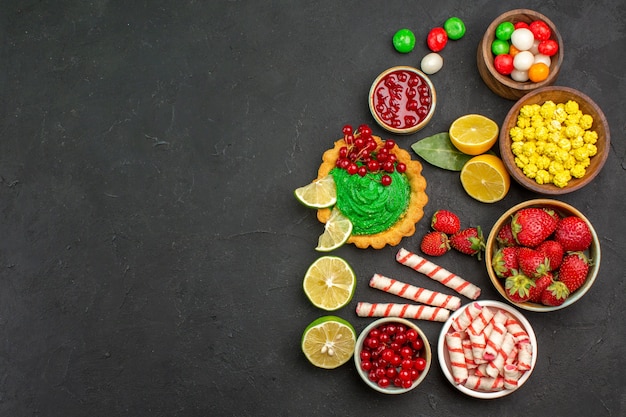 Top view yummy cake with candies and fruits on dark background cookie biscuit sweet free place