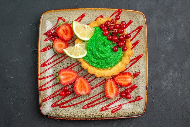 Top view yummy cake with green cream and strawberries on dark background sweet dessert tea